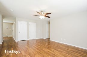 Winston-Salem house for rent - A spacious room with a ceiling fan and wooden flooring.