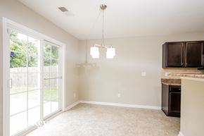 Winston-Salem house for rent - A well-lit, empty room with a fireplace and a window with a view of a fence and trees.