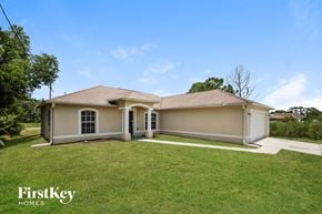 Lehigh Acres house for rent - a beige house with a lawn and a driveway