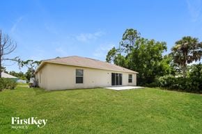 Lehigh Acres house for rent - a small white house with a grassy yard and trees