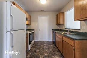 Indianapolis house for rent - a kitchen with white appliances and wooden cabinets and a refrigerator