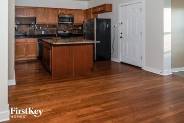 Chicago house for rent - a kitchen with wood floors and a black refrigerator