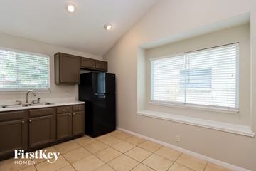 Spring house for rent - A kitchen with brown cabinets and a black refrigerator.