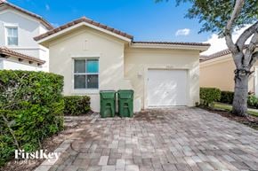 Homestead house for rent - a home with a garage and a driveway with two green trash cans