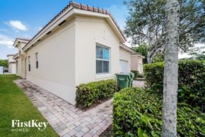 Homestead house for rent - a white house with a driveway and a green trash can