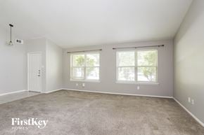 Humble house for rent - A spacious room with a carpeted floor and two windows.