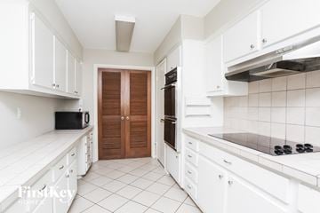 Humble house for rent - A kitchen with white cabinets and a black microwave.