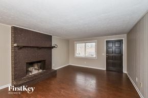 Douglasville house for rent - an empty living room with a brick fireplace and wooden floors