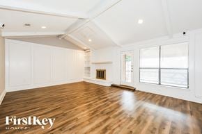Fort Worth house for rent - A spacious room with wooden floors and white walls, with a large window on the right side.