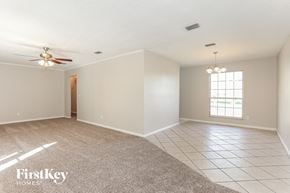 Jacksonville house for rent - an empty living room with a ceiling fan and a window