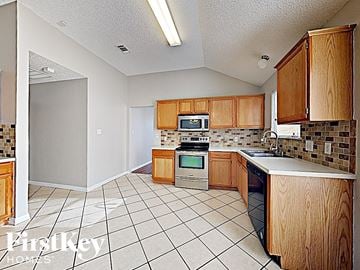 Fort Worth house for rent - A kitchen with wooden cabinets and a tiled floor.