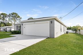 Port St. Lucie house for rent - a white house with a white garage door and a lawn