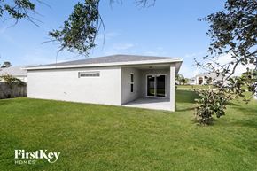Port St. Lucie house for rent - a small white house with a grass lawn and a tree