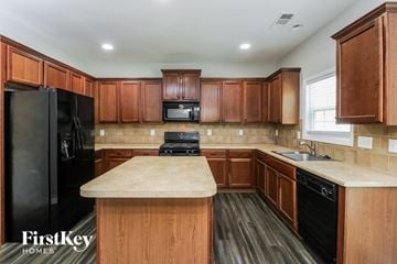 Atlanta house for rent - A kitchen with wooden cabinets and a black fridge.