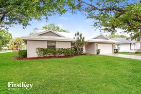 Coral Springs house for rent - A well-maintained lawn in front of a house with the logo "FirstKey HOMES" on the bottom left.
