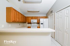 Parrish house for rent - a kitchen with white countertops and wooden cabinets and white appliances