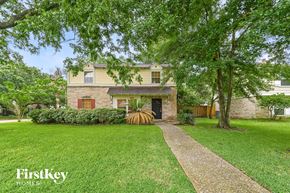 Spring house for rent - A house with a brown door and a small porch is surrounded by trees.