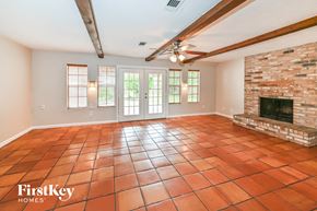 Spring house for rent - A large empty room with a fireplace and a tiled floor.