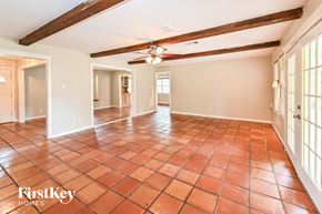 Spring house for rent - A spacious room with a tiled floor and wooden beams on the ceiling.