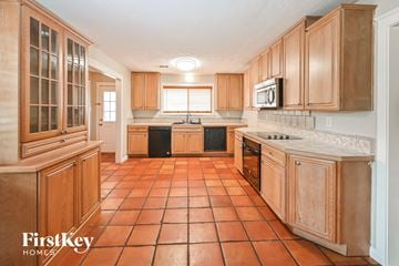Spring house for rent - A kitchen with wooden cabinets and tile flooring.