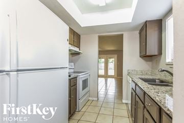 Titusville house for rent - a kitchen with white cabinets and a white refrigerator and a sink