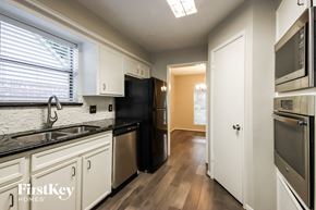Humble house for rent - a kitchen with black counter tops and white cabinets and a black refrigerator