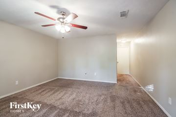 Humble house for rent - the living room is spacious with carpet and a ceiling fan