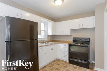 Independence house for rent - A kitchen with a black fridge and stove and white cabinets.