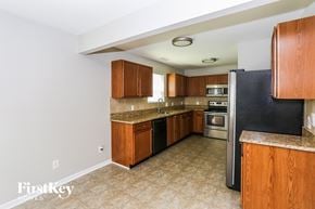 Charlotte house for rent - a kitchen with wooden cabinets and a black refrigerator