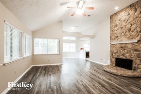 Kingwood house for rent - A spacious room with a stone fireplace and wooden floors.