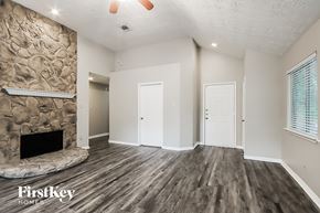 Kingwood house for rent - A room with a stone fireplace and wood flooring.