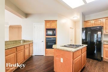 Kingwood house for rent - a kitchen with wooden cabinets and a black refrigerator