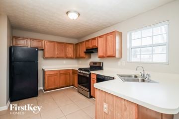 Mcdonough house for rent - A kitchen with wooden cabinets and a black fridge.