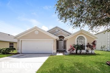 Kissimmee house for rent - a house with a white garage door and a lawn