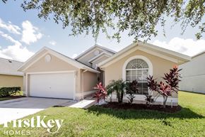 Kissimmee house for rent - a beige house with a lawn and a garage