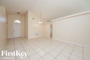 Kissimmee house for rent - a spacious living room with white tile flooring and a white door