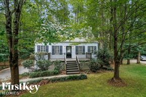 Marietta house for rent - A white house with a black fence and trees in front.