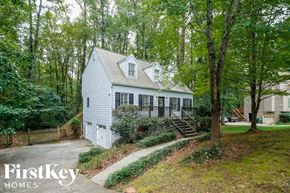 Marietta house for rent - A house with a white exterior is surrounded by trees and has a staircase leading to the front door.