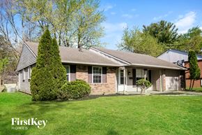 Indianapolis house for rent - a white and brick house with a green lawn and trees