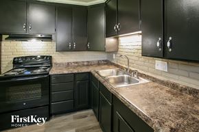 Indianapolis house for rent - a kitchen with black cabinets and granite counter tops and a sink