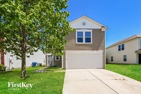 Indianapolis house for rent - a tan house with a white garage door and a tree