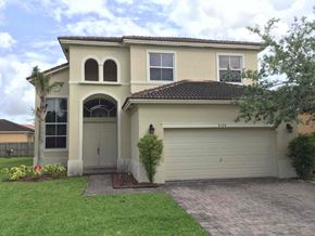 Homestead house for rent - a house with a garage door and a lawn
