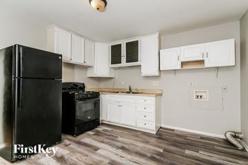 Indianapolis house for rent - a kitchen with white cabinets and a black refrigerator