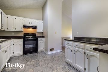 Powder Springs house for rent - A kitchen with white cabinets and black appliances.