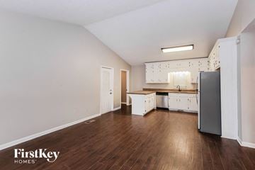 Gainesville house for rent - a renovated kitchen with white cabinets and white appliances and wood floors