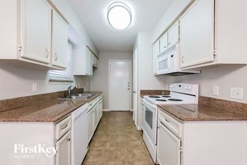 Spring house for rent - a kitchen with white cabinets and white appliances and granite counter tops