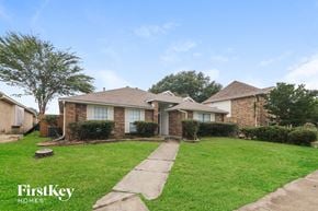 Garland house for rent - the front of a brick house with a lawn and a sidewalk