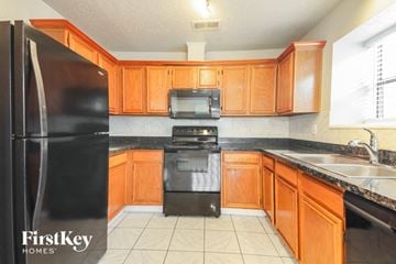Garland house for rent - a kitchen with black appliances and wooden cabinets