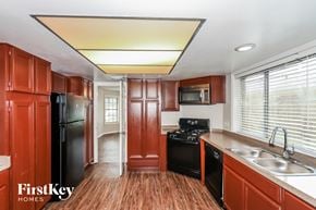 Houston house for rent - a kitchen with wooden cabinets and black appliances and a sink
