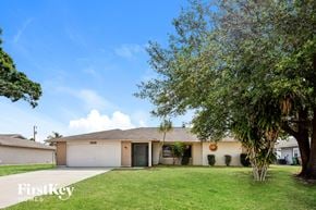 Cape Coral house for rent - a white house with a lawn and a tree